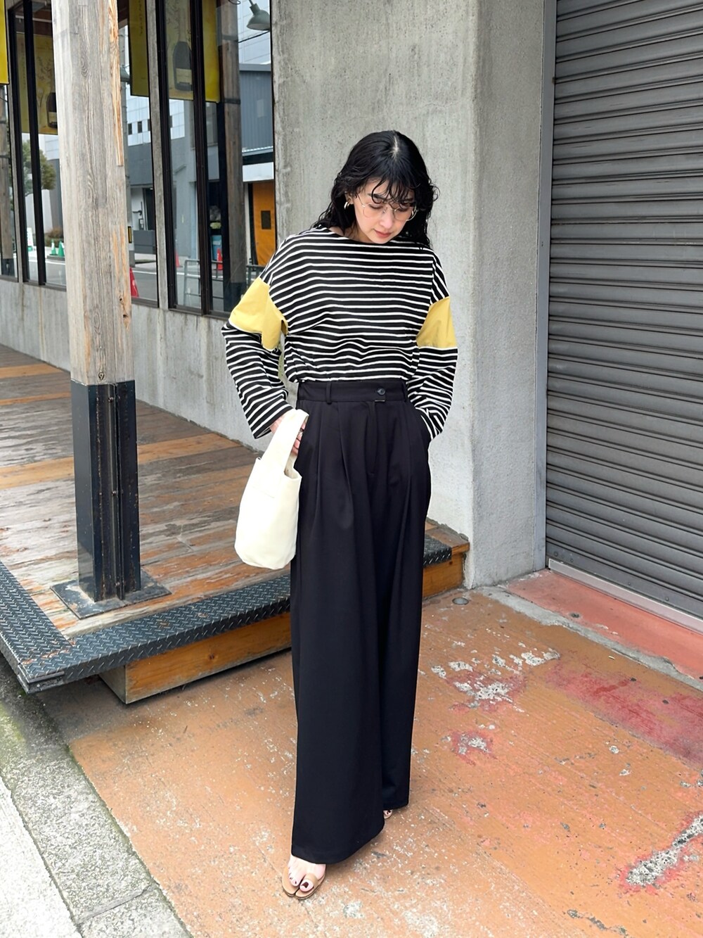 イエロー系のTシャツ/カットソー、ブラック系のスラックス、ブラウン系のサンダルを着用したレディースの春コーディネートの4枚目の写真