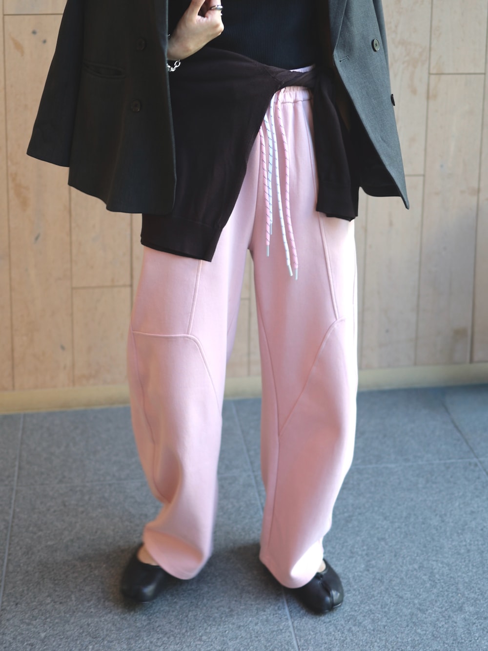 ピンク系のスウェットパンツ、グレー系のテーラードジャケット、ブラック系のバレエシューズを着用したレディースの秋コーディネートの3枚目の写真