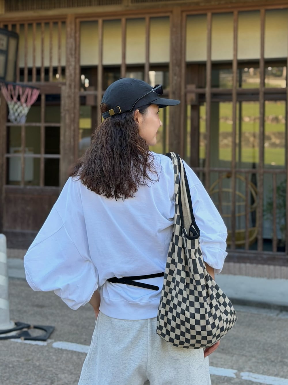 ホワイト系のTシャツ/カットソー、グレー系のスウェットパンツ、ブラック系のトートバッグを着用したレディースの秋コーディネートの3枚目の写真