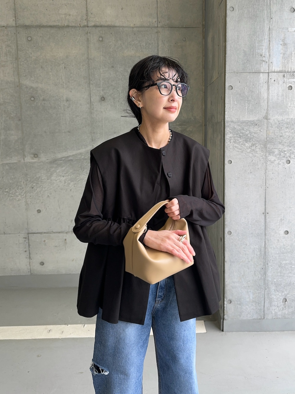 ブラック系のベスト、ブラック系のTシャツ/カットソー、ブルー系のデニムパンツを着用したレディースの春コーディネートの3枚目の写真