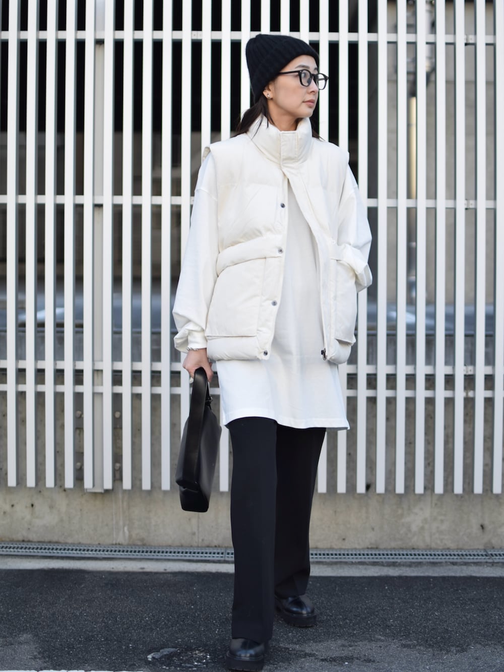 ホワイト系のダウンベスト、ブラック系のその他パンツ、ブラック系のショルダーバッグを着用したレディースの冬コーディネートの5枚目の写真