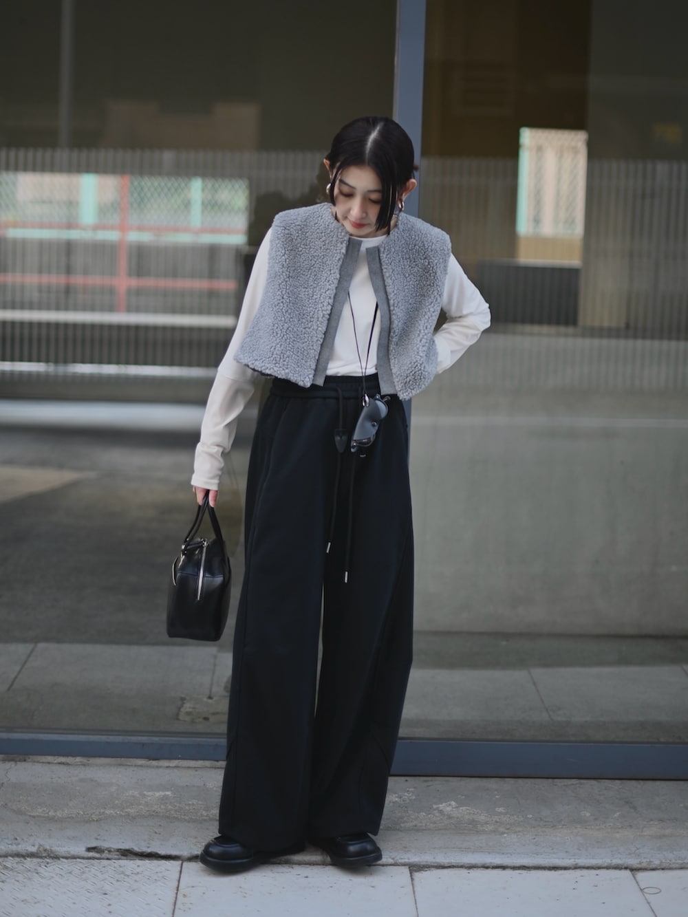 グレー系のベスト、ブラック系のスウェットパンツ、ブラック系のメガネを着用したレディースの冬コーディネートの2枚目の写真