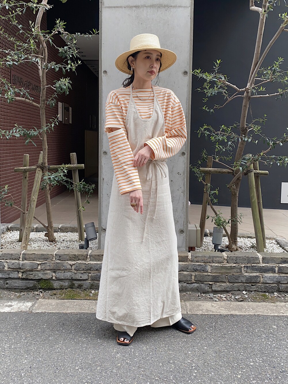 オレンジ系のTシャツ/カットソー、ベージュ系のハット、ブラウン系の口紅/リップティント/グロスを着用したレディースの春コーディネートの2枚目の写真