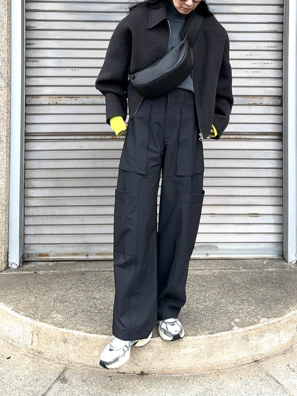 グレー系のブルゾン、ブラック系のショルダーバッグ、グリーン系のカーゴパンツを着用したレディースの冬コーディネートの3枚目の写真