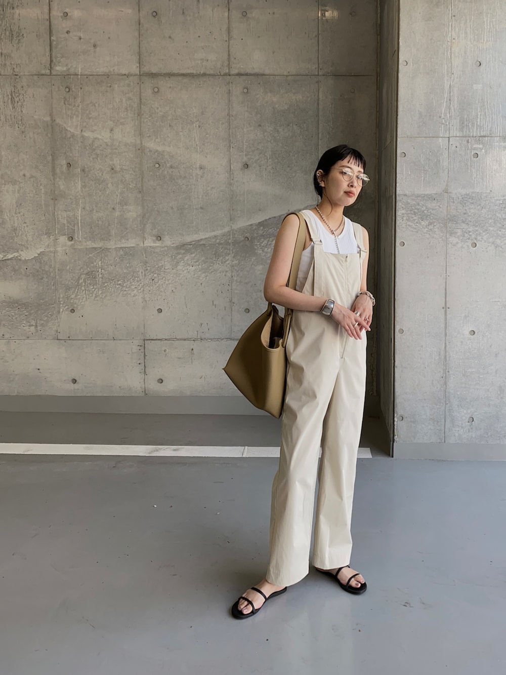 ホワイト系のサロペット/オーバーオール、ベージュ系のハンドバッグ、ブラック系のサンダルを着用したレディースの夏コーディネートの2枚目の写真