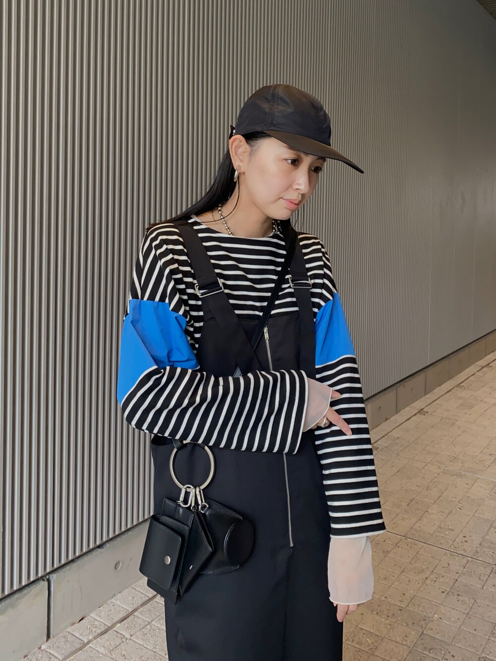 ブルー系のTシャツ/カットソー、ブラック系のジャンパースカート、ブラック系のショルダーバッグを着用したレディースの春コーディネートの2枚目の写真