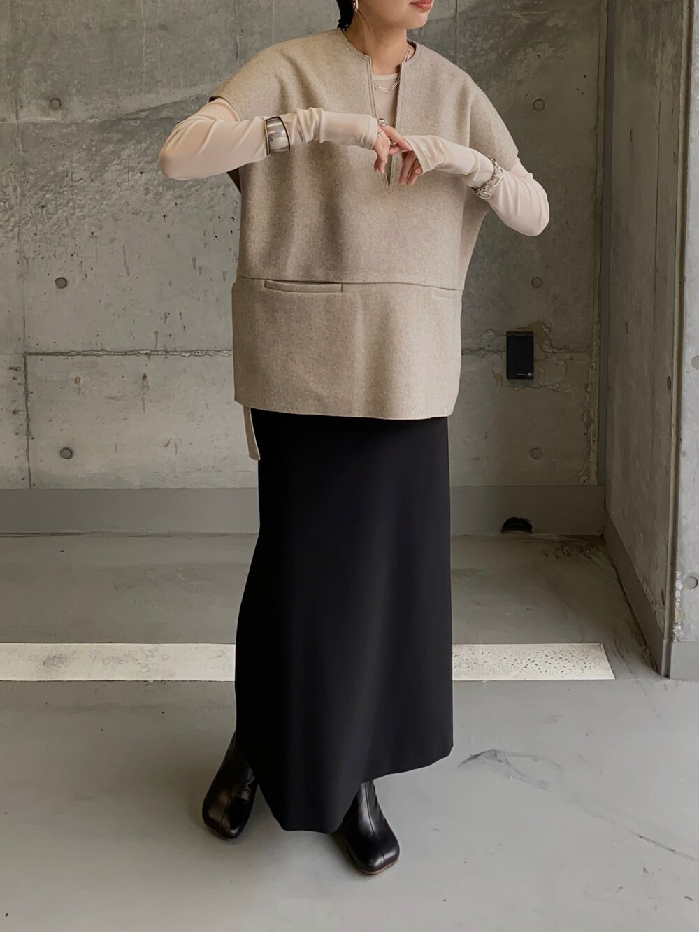 ベージュ系のベスト、ブラック系のスカート、ブラック系のブーツを着用したレディースの秋コーディネートの4枚目の写真