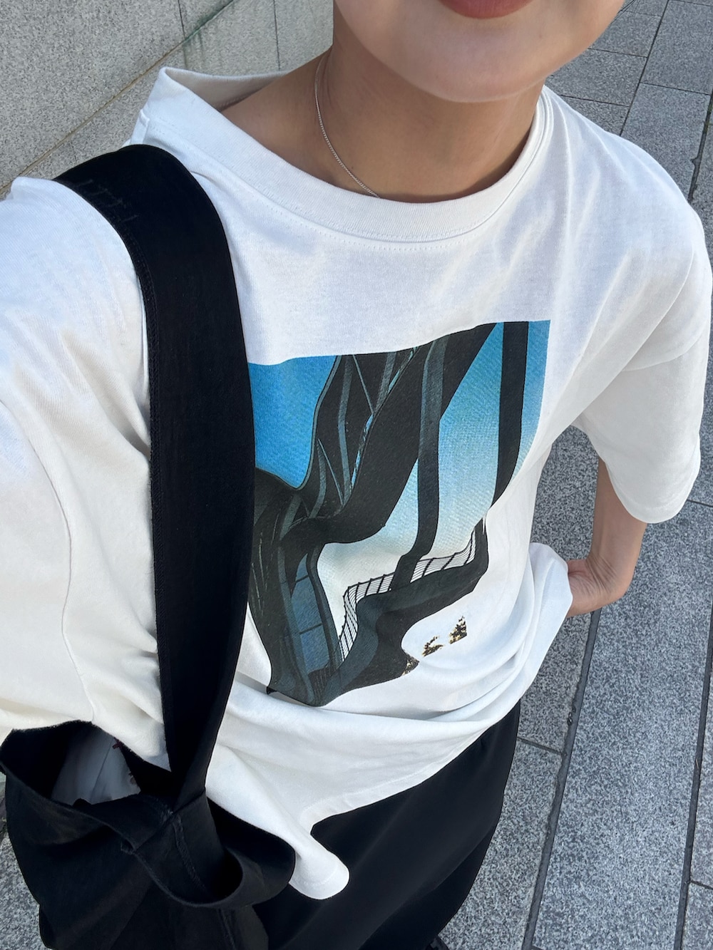 ホワイト系のTシャツ/カットソー、ブラック系のスカート、ブラック系のトートバッグを着用したレディースの春コーディネートの3枚目の写真