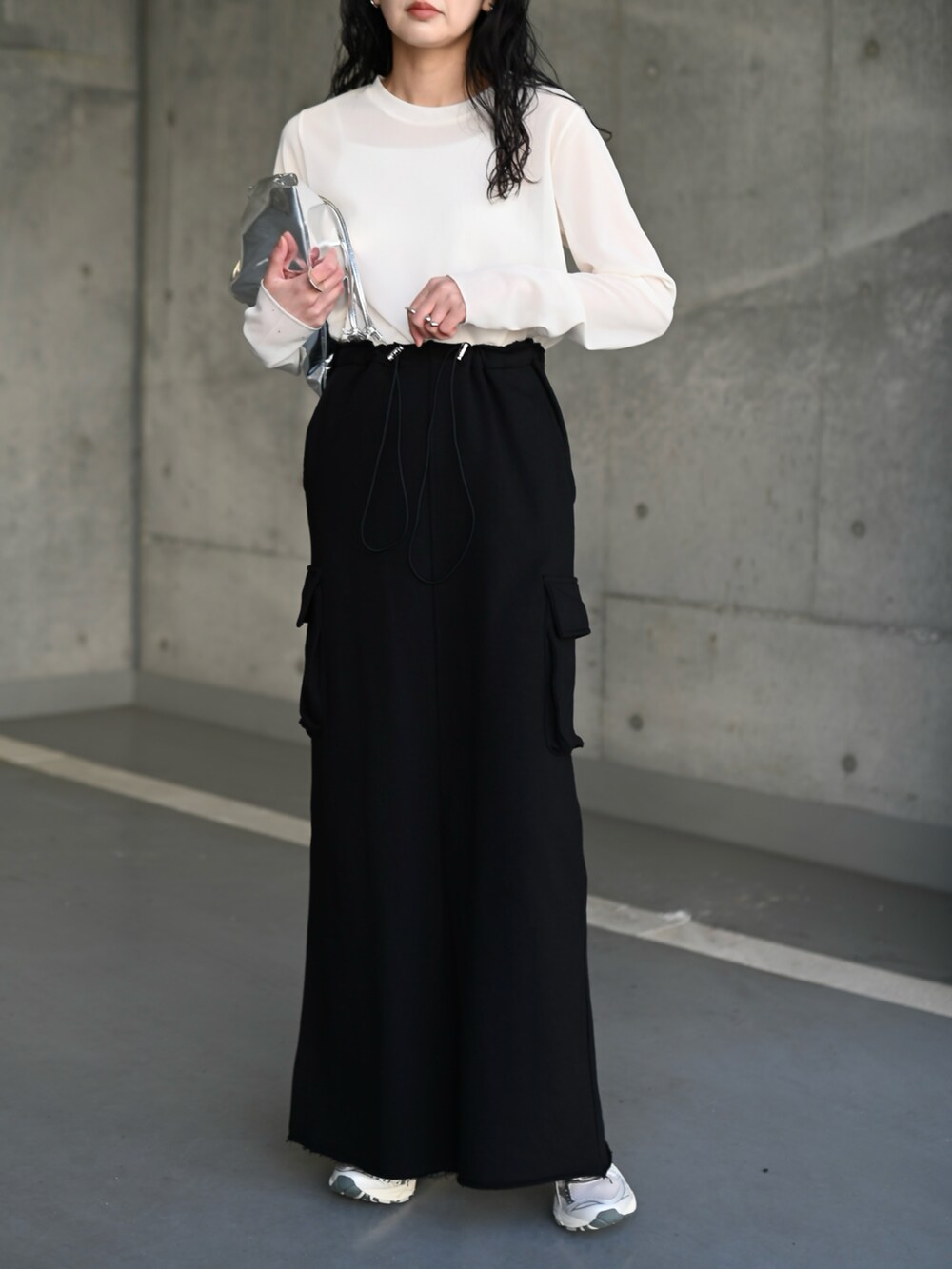 ホワイト系のTシャツ/カットソー、ブラック系のスカート、シルバー系のスニーカーを着用したレディースの夏コーディネートの2枚目の写真