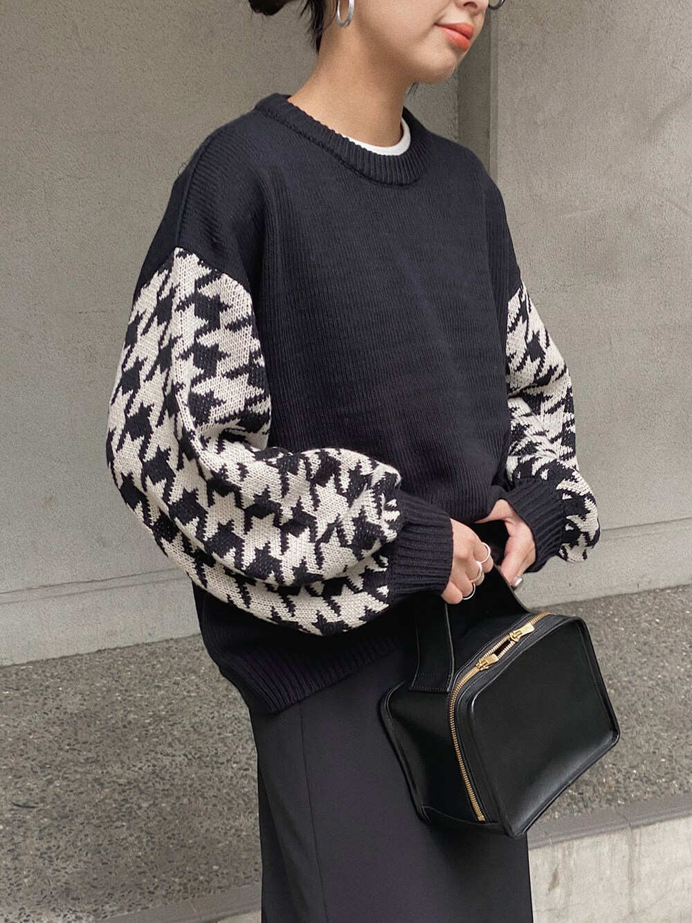 ブラック系のニット/セーター、ブラック系のダウンベスト、ブラック系のスカートを着用したレディースの冬コーディネートの3枚目の写真