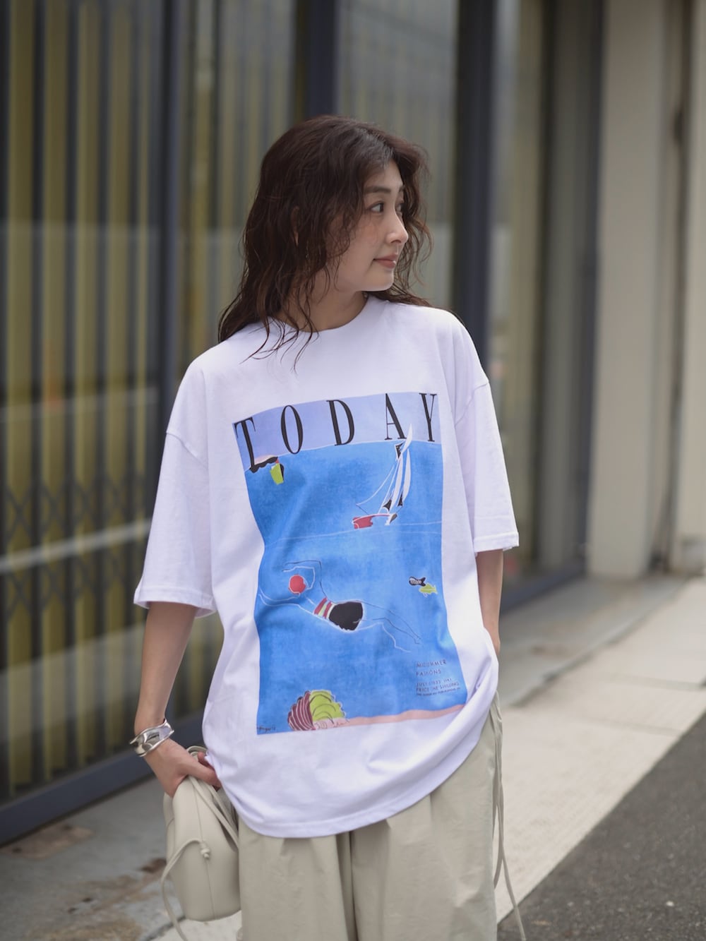 ホワイト系のTシャツ/カットソー、ホワイト系のショルダーバッグ、グレー系のパンツを着用したレディースの夏コーディネートの4枚目の写真