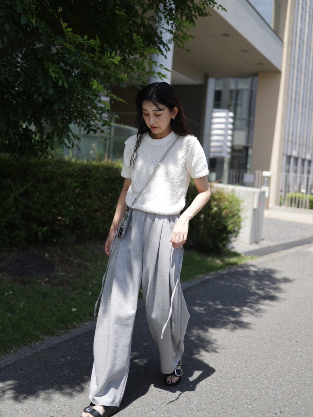 グレー系のスウェットパンツ、ホワイト系のニット/セーター、ブラック系のサンダルを着用したレディースの夏コーディネートの3枚目の写真