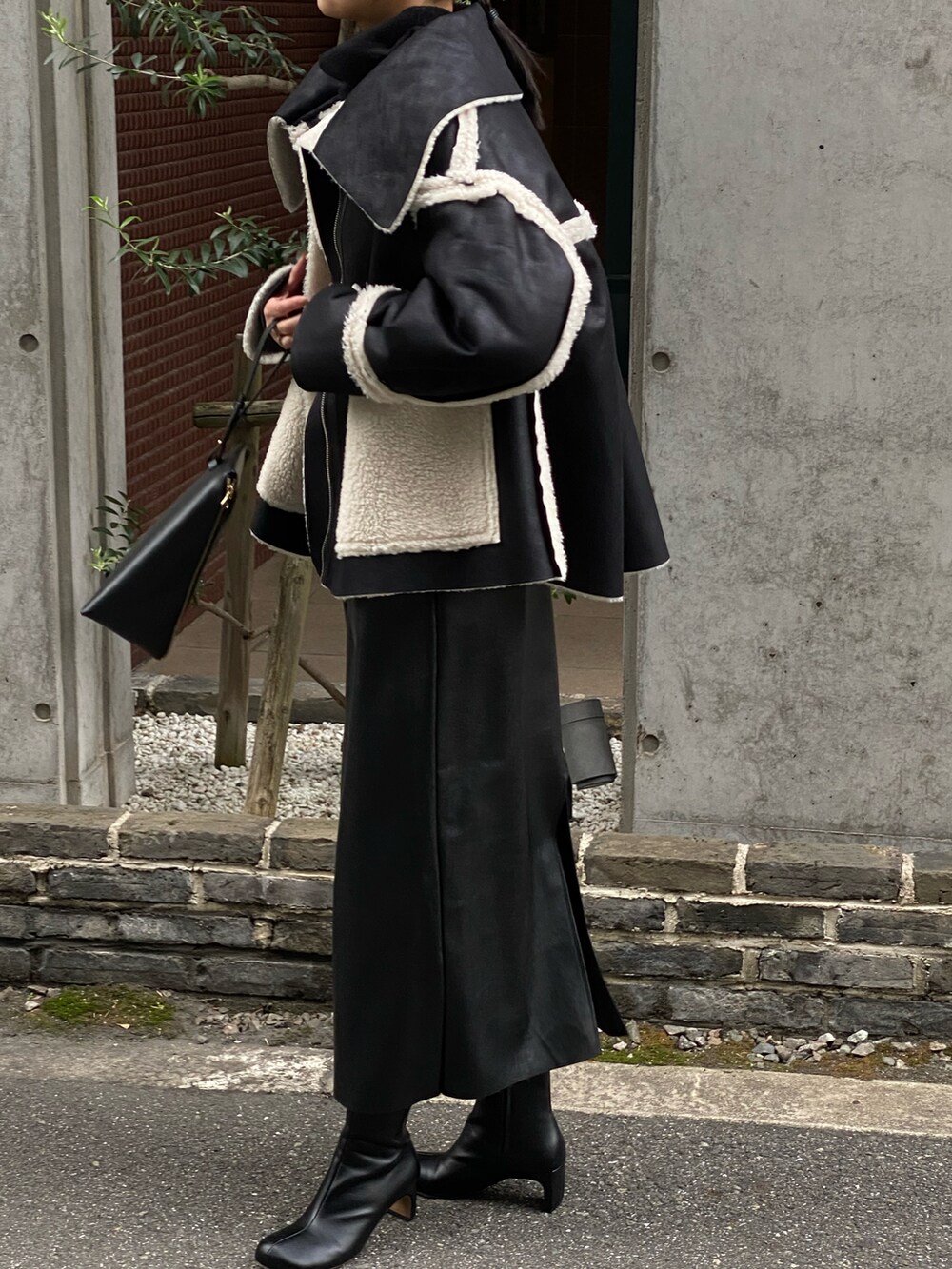 ブラック系のニット/セーター、ブラック系のブーツ、ブラック系のその他アウターを着用したレディースの秋コーディネートの5枚目の写真