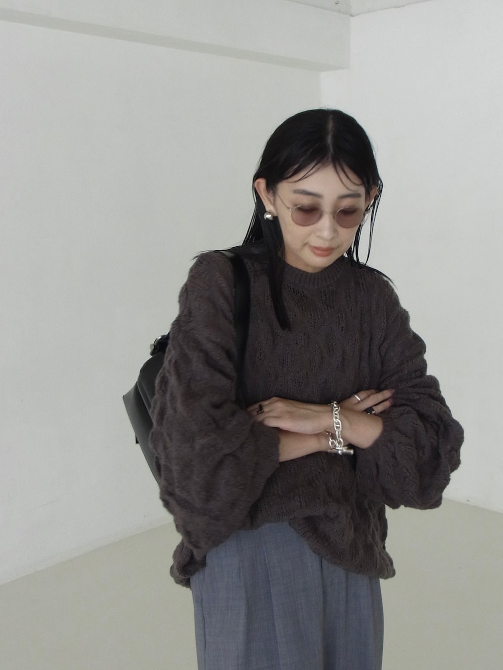 グレー系のニット/セーター、ブラック系のショルダーバッグ、グレー系のスラックスを着用したレディースの秋コーディネートの3枚目の写真