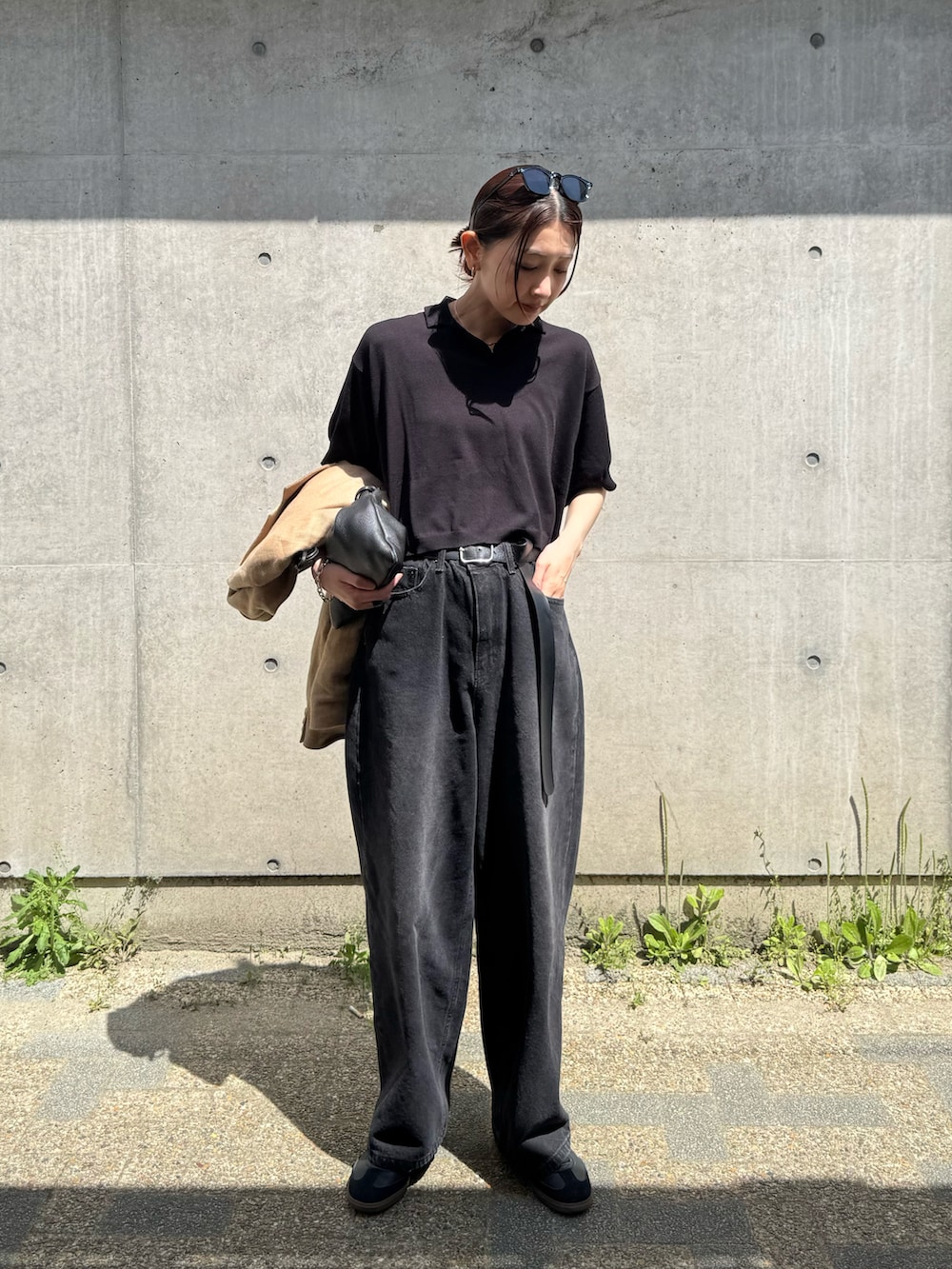 ブラック系のポロシャツ、ブラック系のデニムパンツ、ブラック系のスニーカーを着用したレディースの春コーディネートの3枚目の写真