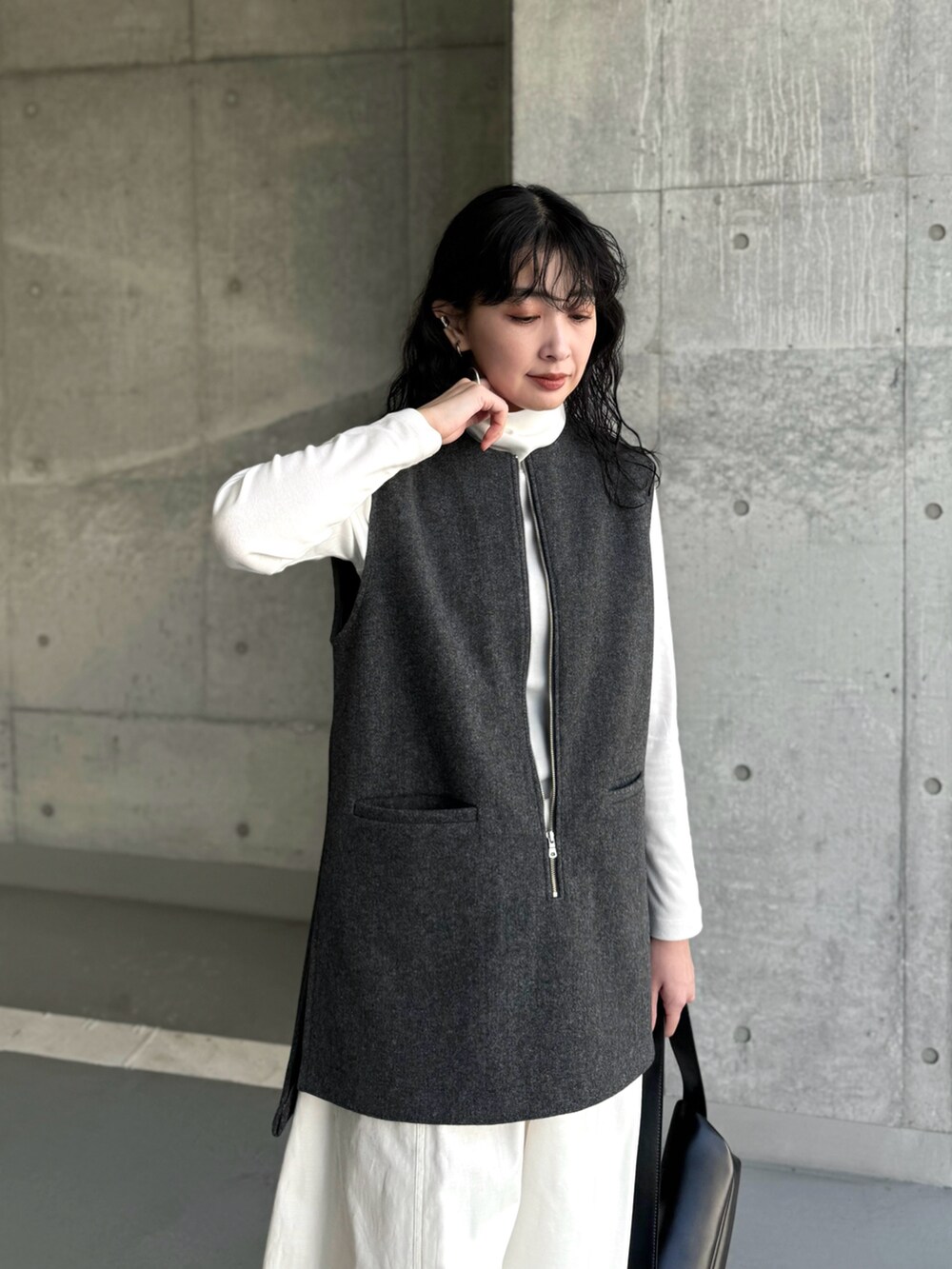 グレー系のベスト、ホワイト系のチノパンツ、ブラック系のブーツを着用したレディースの冬コーディネートの3枚目の写真