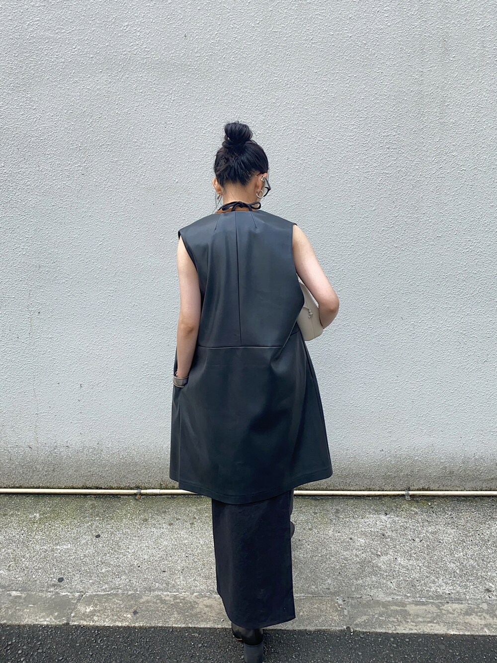 ブラック系のベスト、ブラック系のワンピース、ブラック系のブーツを着用したレディースの秋コーディネートの2枚目の写真