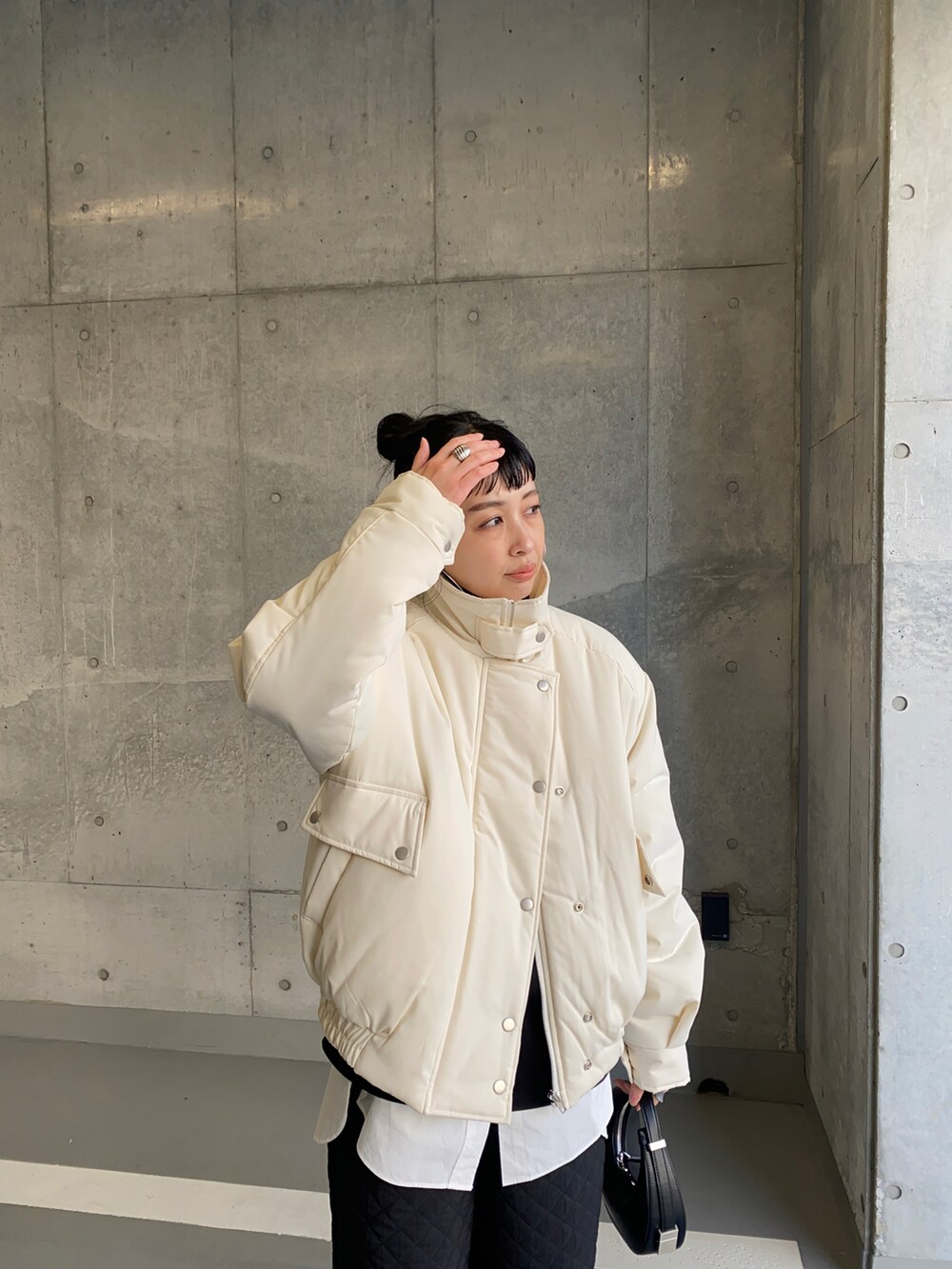 ホワイト系のブルゾン、ブラック系のその他パンツ、ブラック系のハンドバッグを着用したレディースの冬コーディネートの3枚目の写真