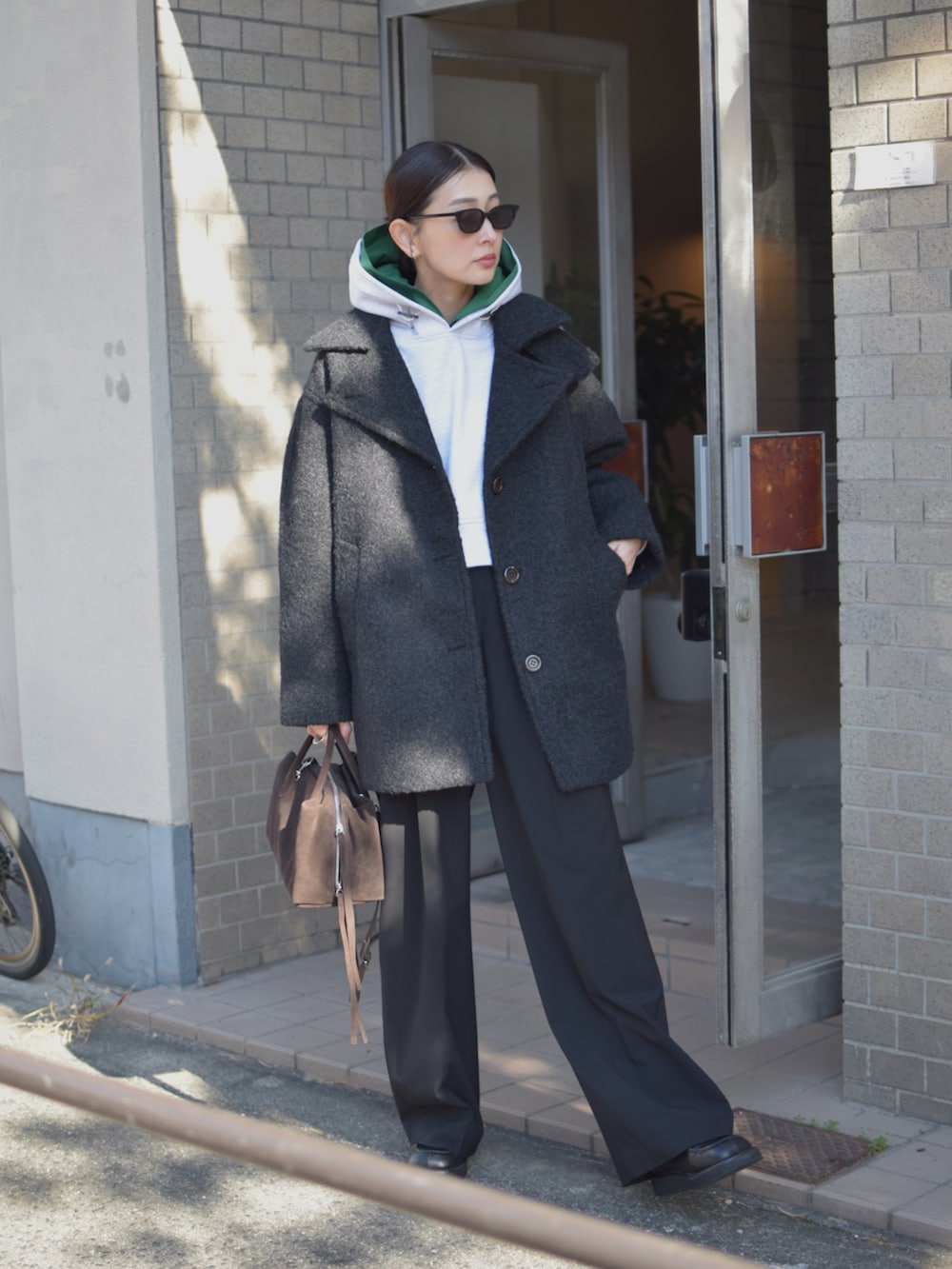 グレー系のパーカー、ブラック系のその他アウター、ブラウン系のトートバッグを着用したレディースの冬コーディネートの2枚目の写真