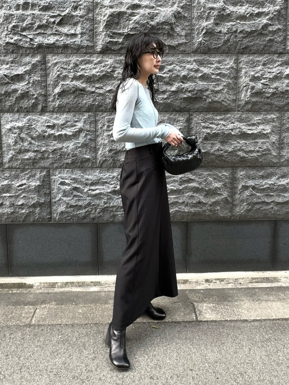 ブラック系のスカート、ブラック系のブーツ、ブラック系のメガネを着用したレディースの春コーディネートの2枚目の写真