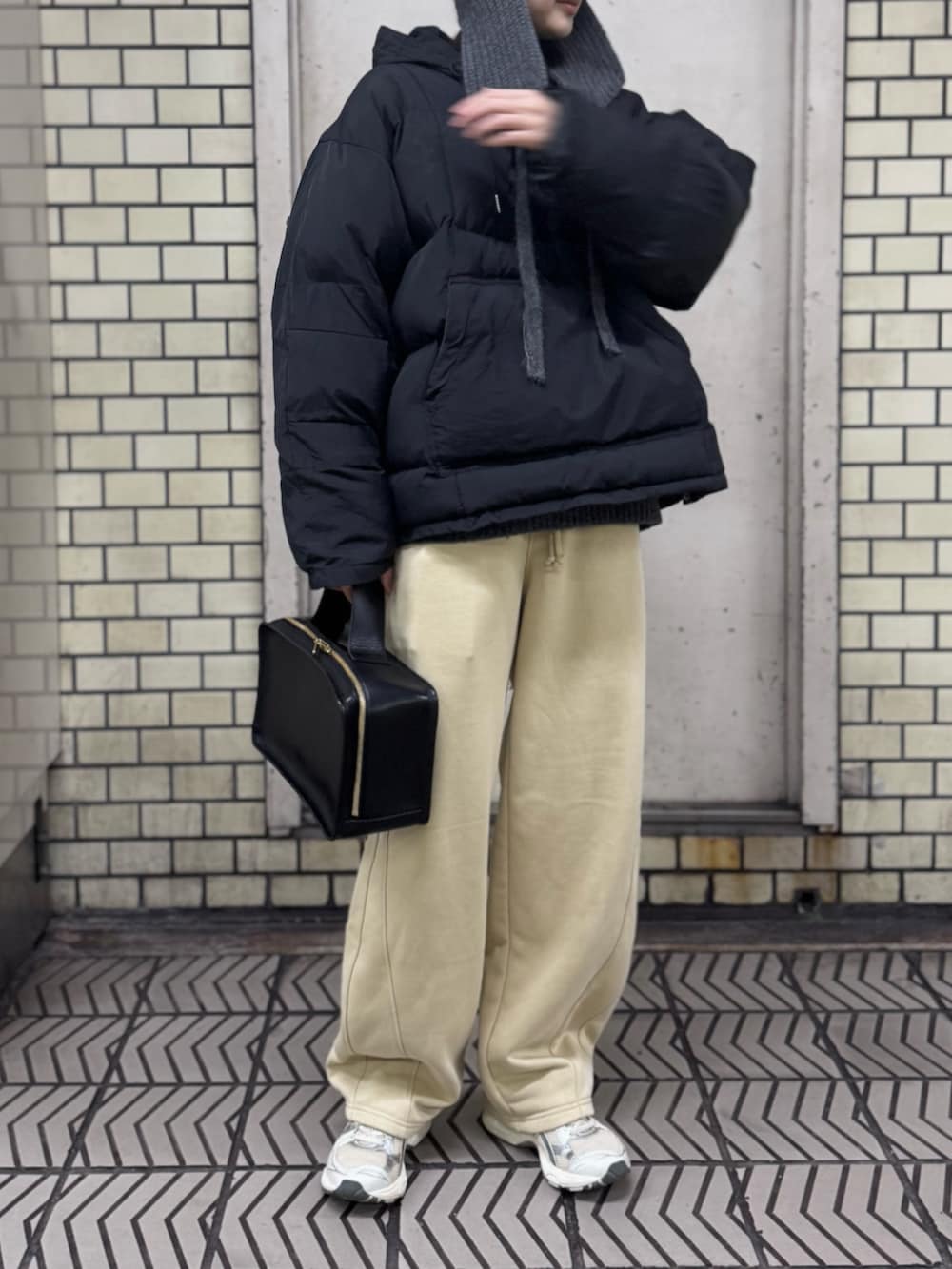シルバー系のスニーカー、ベージュ系のスウェットパンツ、ブラック系のダウンジャケット/コートを着用したレディースの冬コーディネートの2枚目の写真