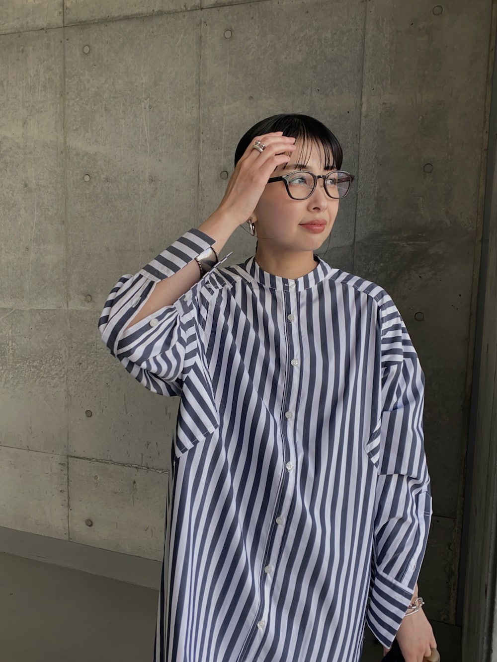 ホワイト系のシャツワンピース、ブラック系のサンダル、シルバー系のリングを着用したレディースの春コーディネートの2枚目の写真