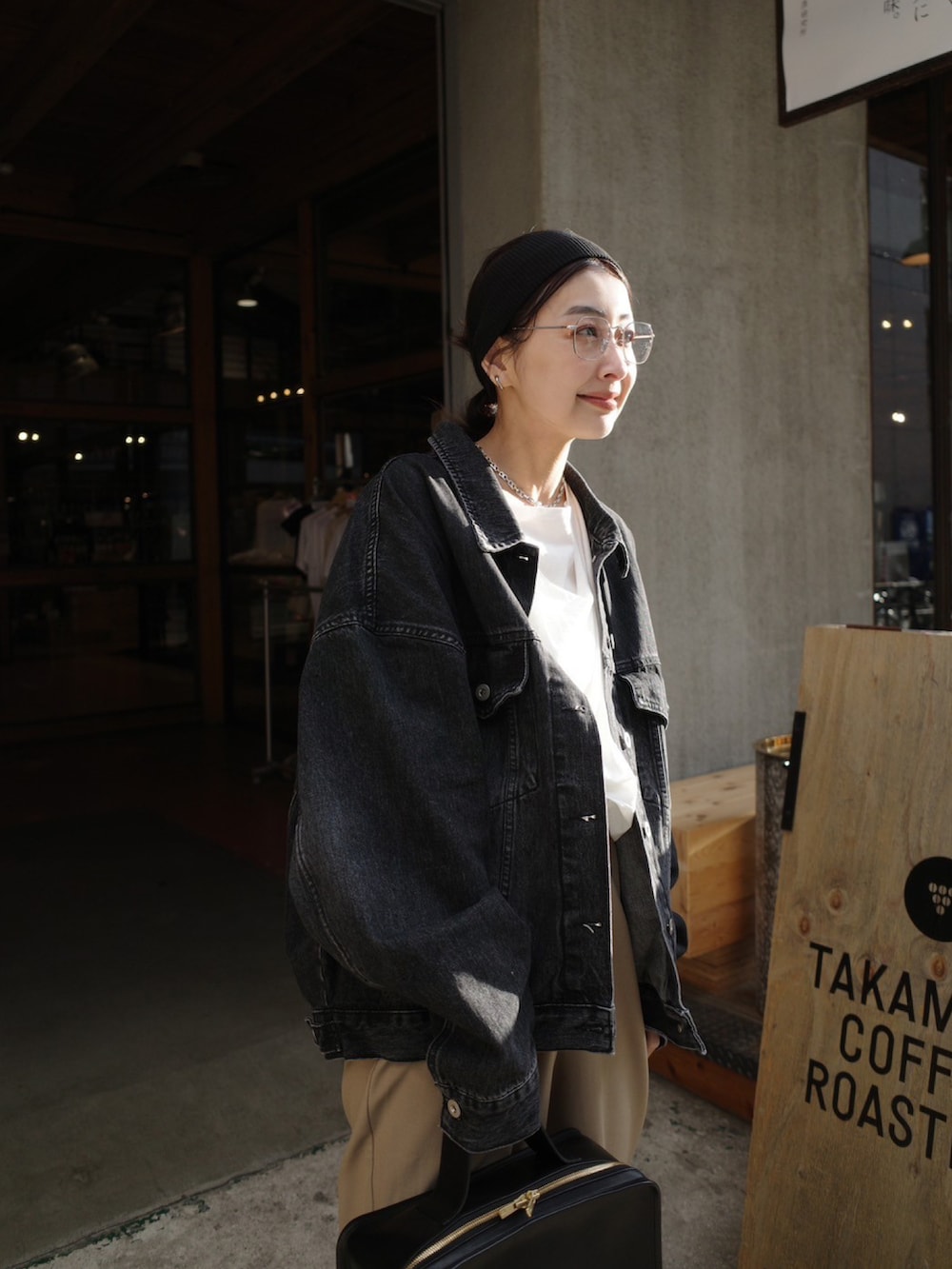 ブラック系のデニムジャケット、ブラック系のハンドバッグ、ブラック系のブーツを着用したレディースの冬コーディネートの3枚目の写真