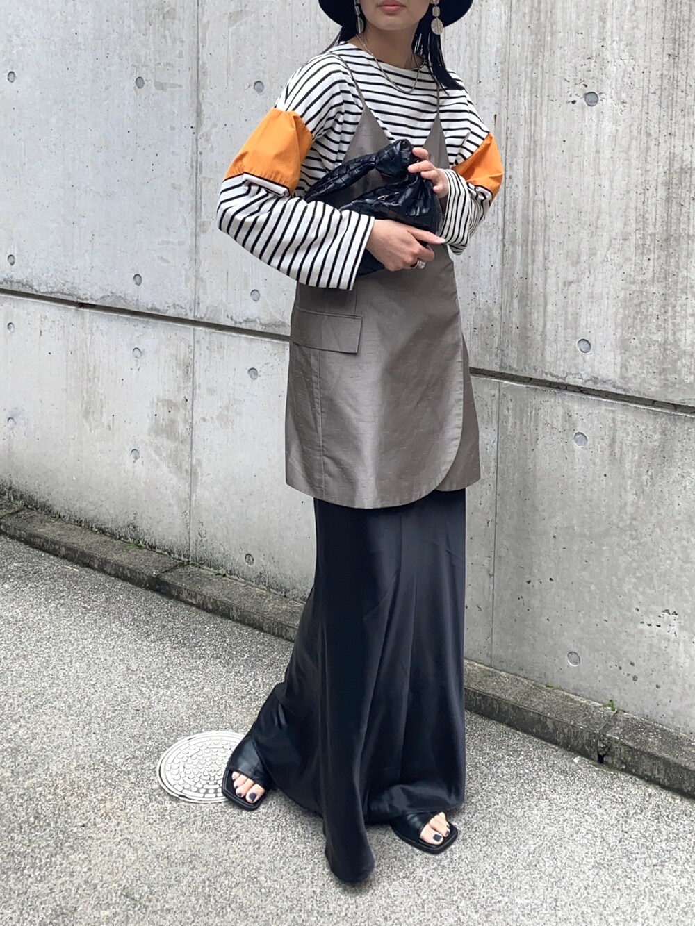 オレンジ系のTシャツ/カットソー、ベージュ系のキャミソール、ブラック系のスカートを着用したレディースの春コーディネートの2枚目の写真