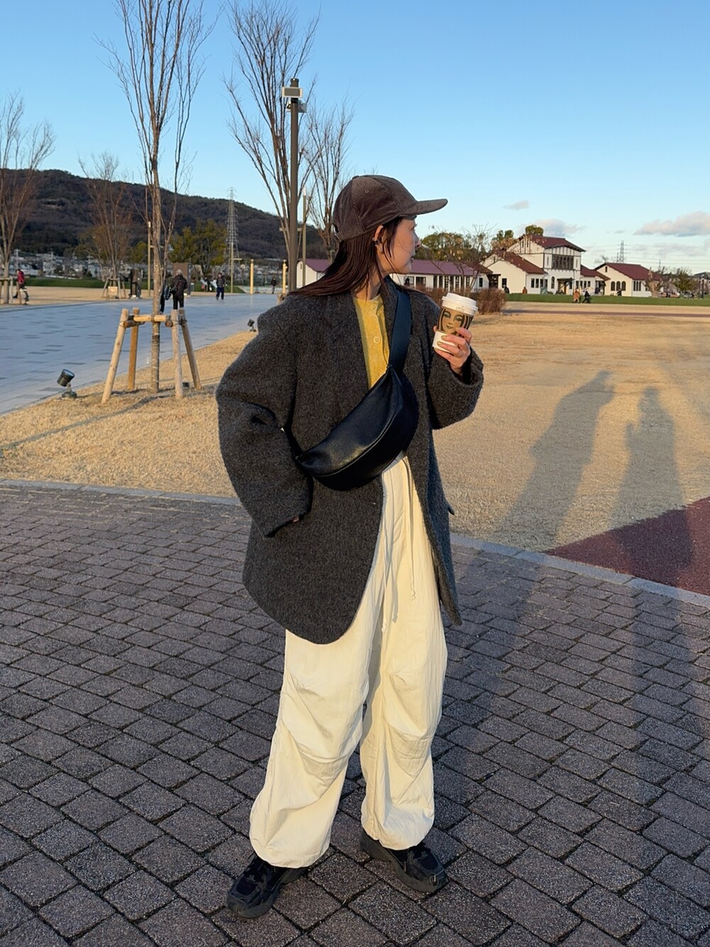 ブラック系のショルダーバッグ、イエロー系のカーディガン/ボレロ、ホワイト系のその他パンツを着用したレディースの冬コーディネートの3枚目の写真