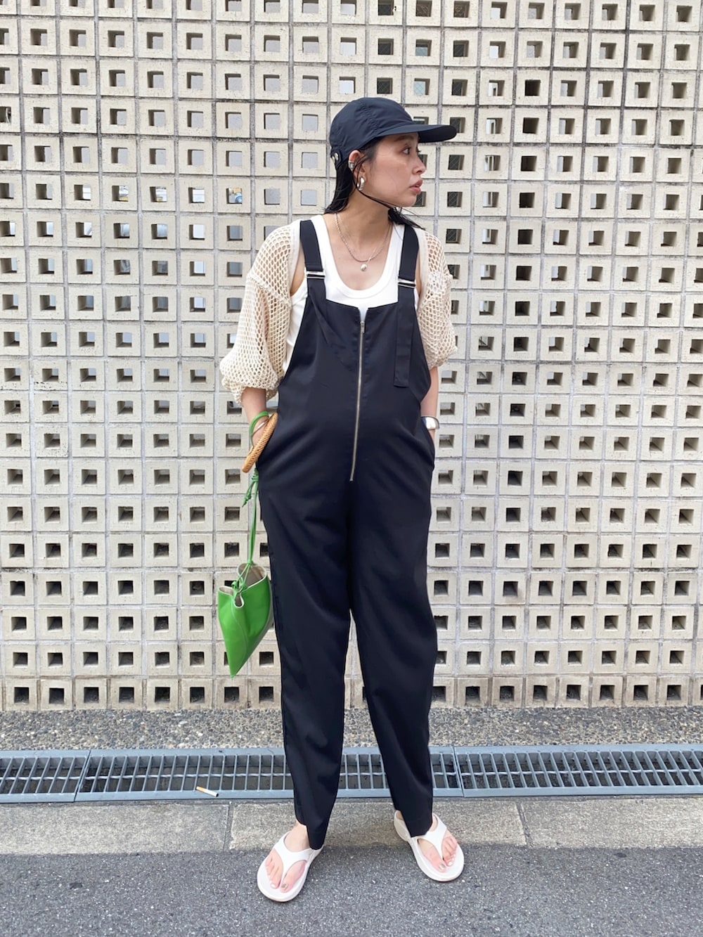 ブラック系のサロペット/オーバーオール、ホワイト系のサンダル、グリーン系のハンドバッグを着用したレディースの夏コーディネートの2枚目の写真