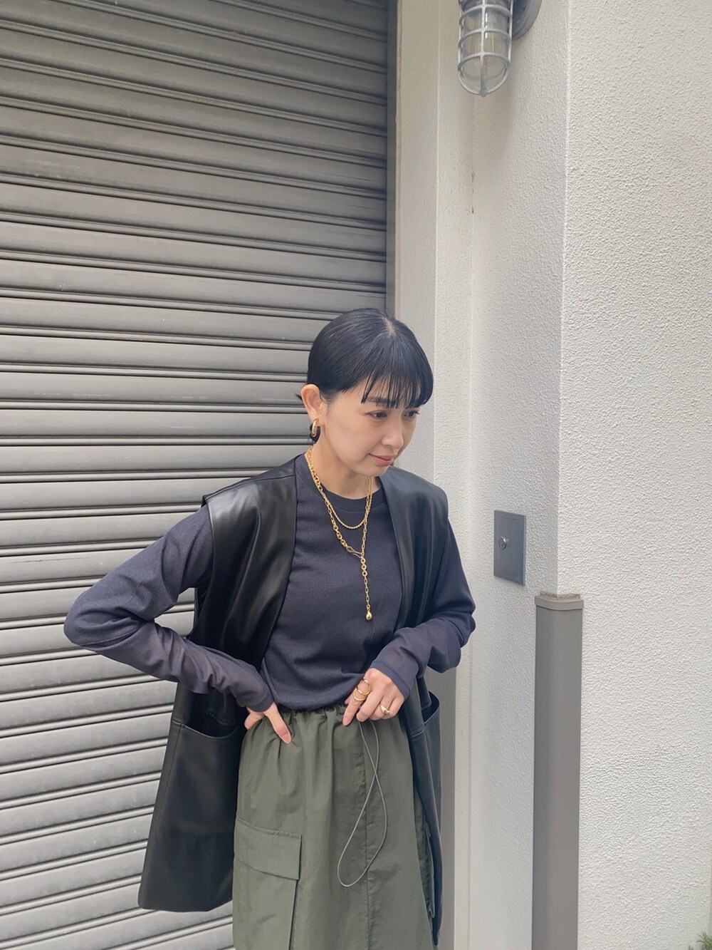 ブラック系のベスト、グリーン系のスカート、ブラック系のTシャツ/カットソーを着用したレディースの春コーディネートの3枚目の写真