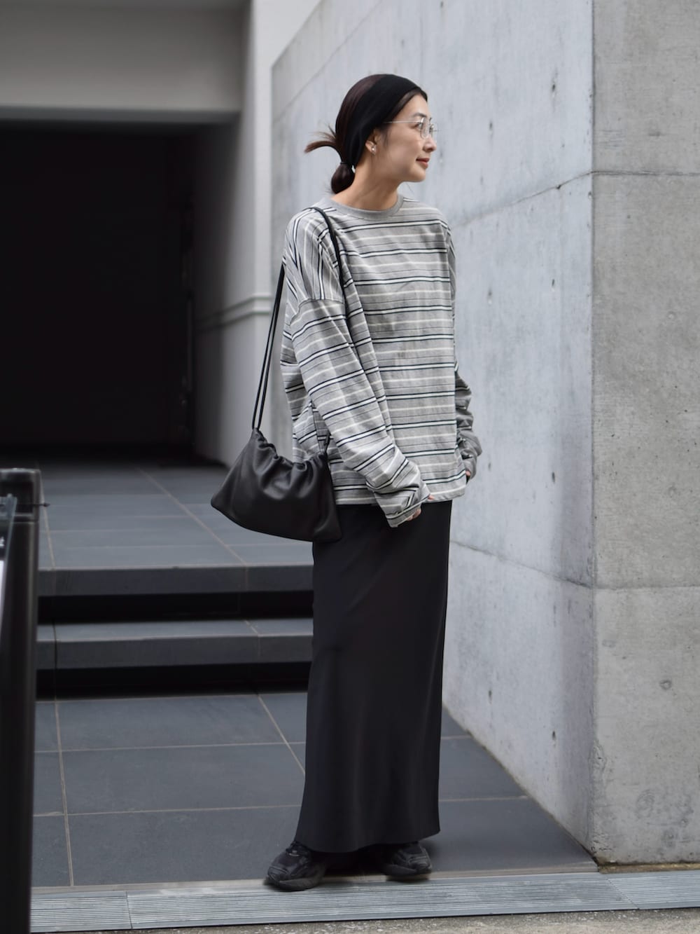 グレー系のTシャツ/カットソー、ブラック系のスカート、ブラック系のスニーカーを着用したレディースの春コーディネートの2枚目の写真