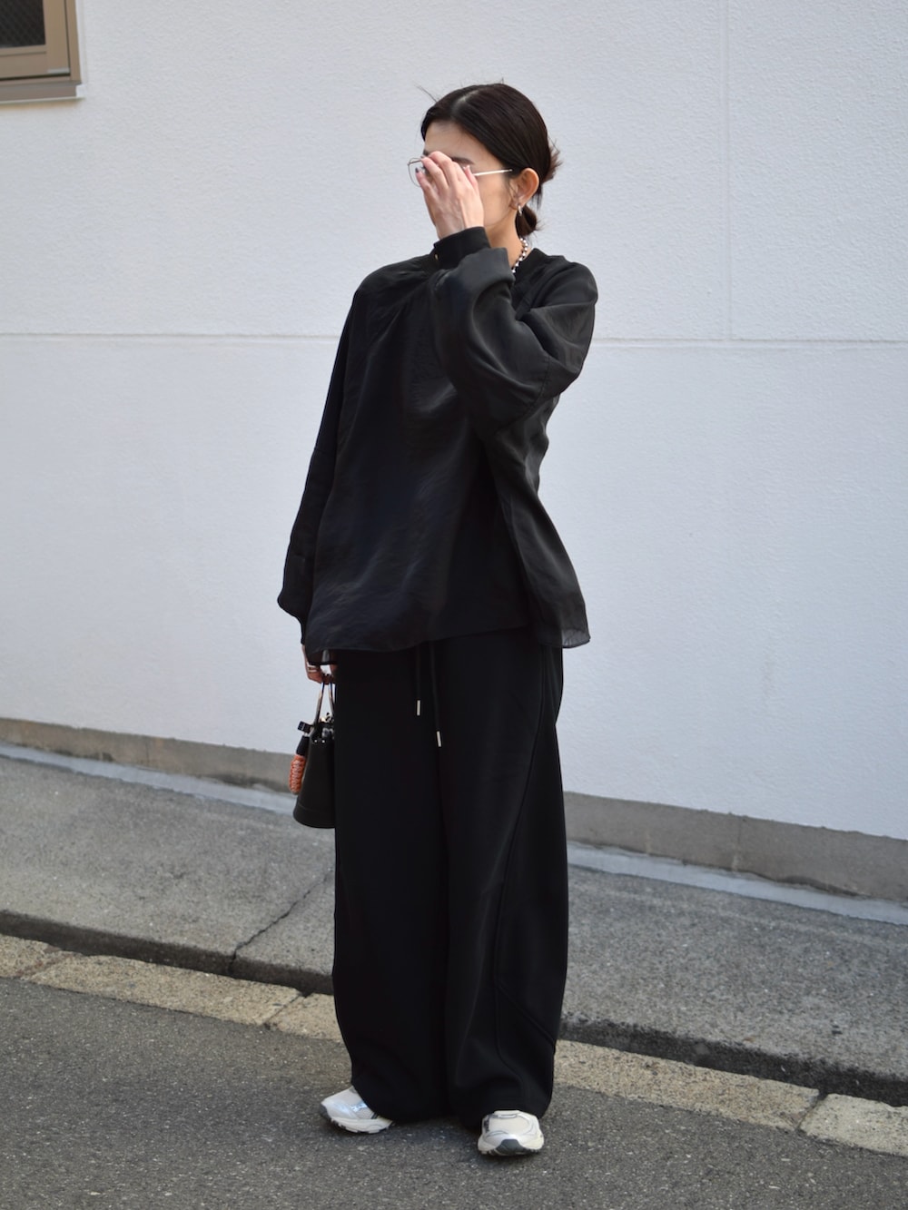 ブラック系のTシャツ/カットソー、ブラック系のスウェットパンツ、シルバー系のスニーカーを着用したレディースの春コーディネートの2枚目の写真