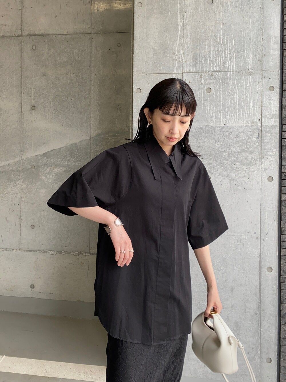 ブラック系のシャツ/ブラウス、ブラック系のスカート、ホワイト系のショルダーバッグを着用したレディースの夏コーディネートの2枚目の写真