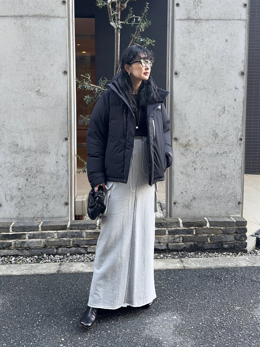 ブラック系のダウンジャケット/コート、グレー系のスカート、ブラック系のブーツを着用したレディースの冬コーディネートの3枚目の写真