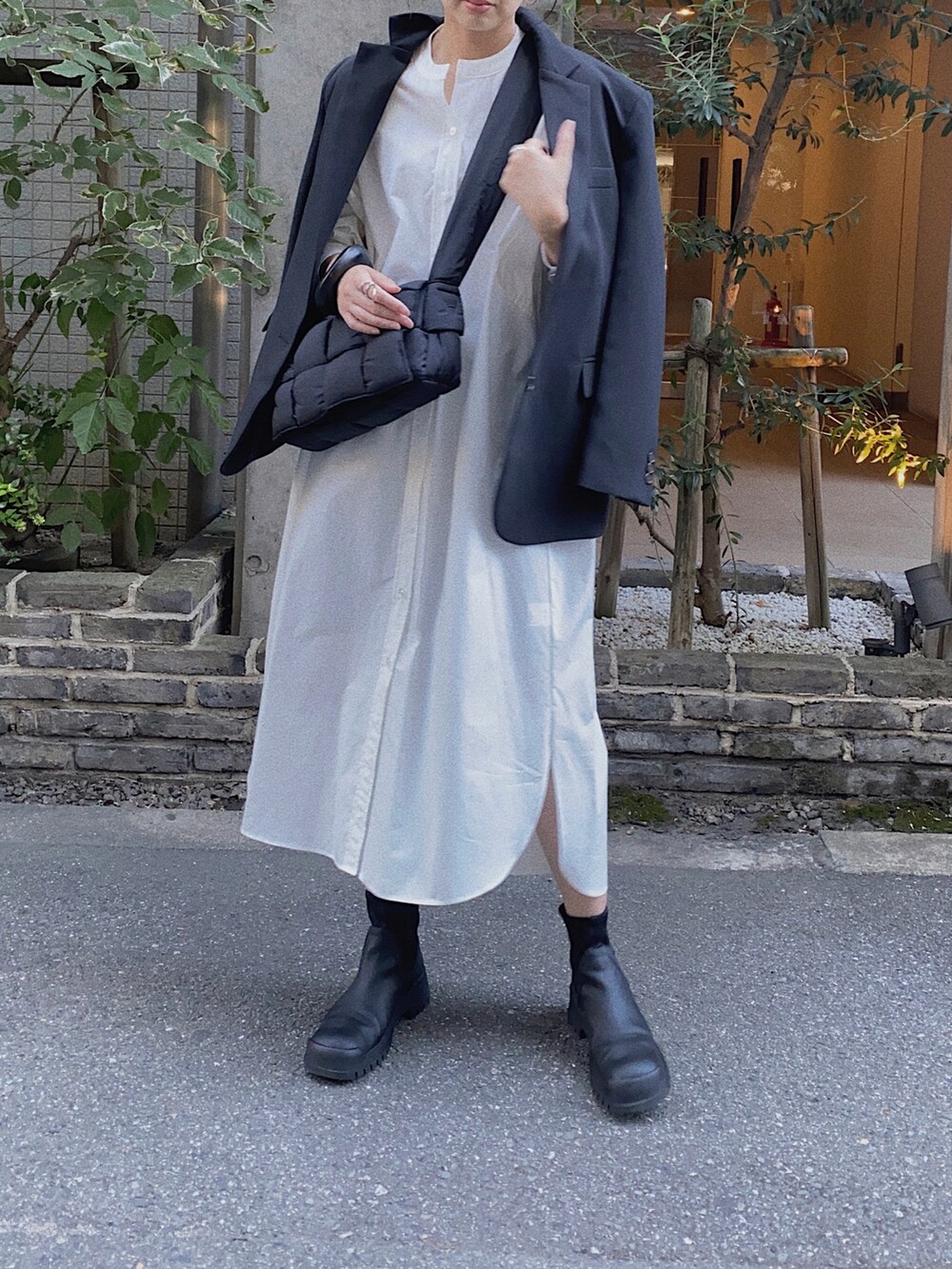 ホワイト系のシャツワンピース、ブラック系のブーツ、ブラック系のテーラードジャケットを着用したレディースの秋コーディネートの2枚目の写真