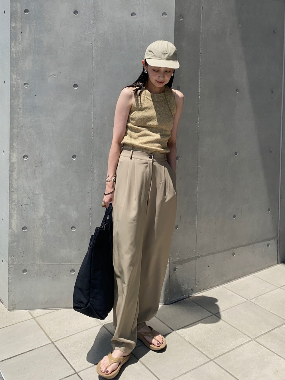 グリーン系のタンクトップ、ブラック系のトートバッグ、ベージュ系のサンダルを着用したレディースの夏コーディネートの3枚目の写真