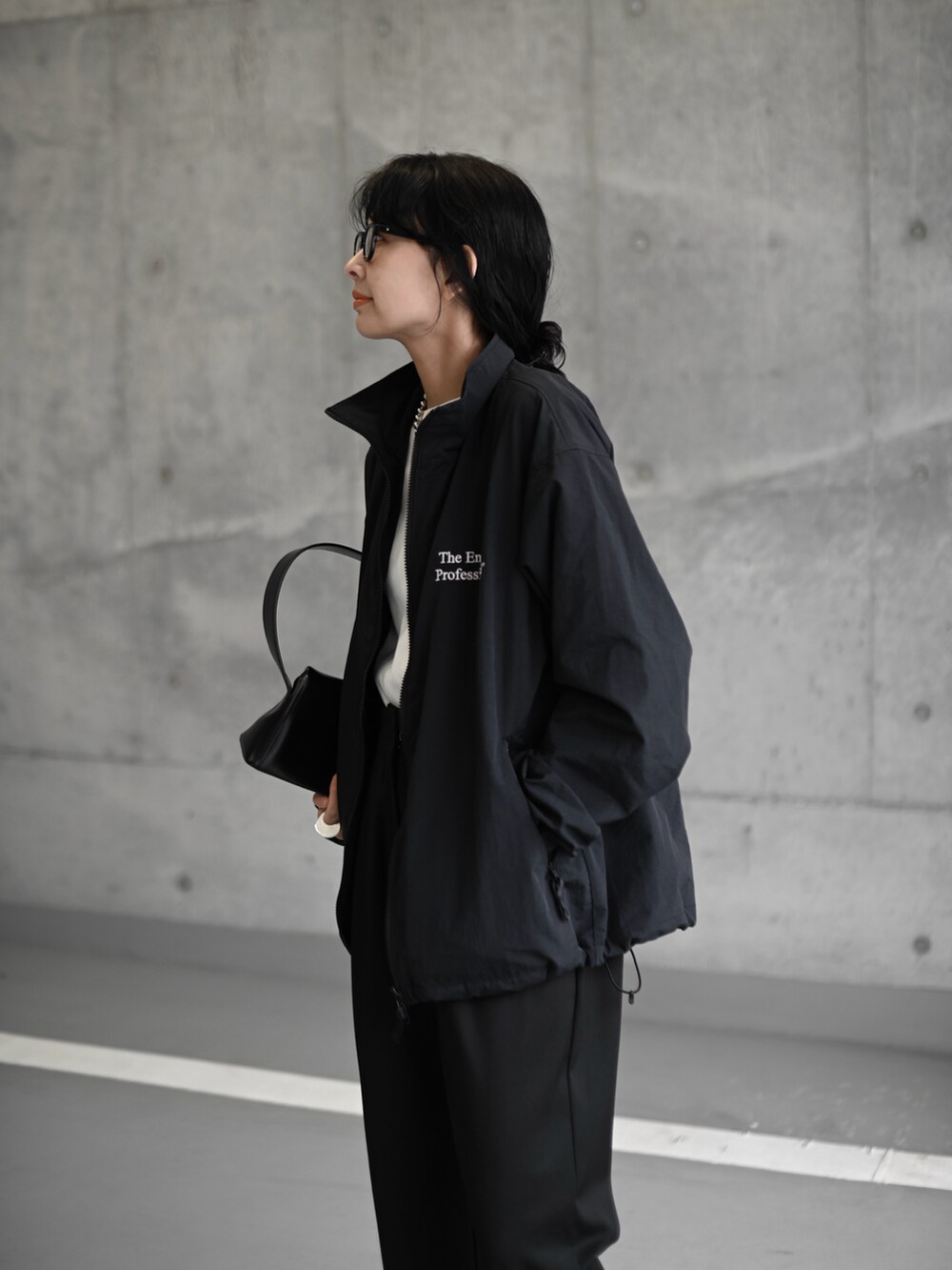 ブラック系のナイロンジャケット、ブラック系のスラックス、ブラック系のブーツを着用したレディースの冬コーディネートの3枚目の写真