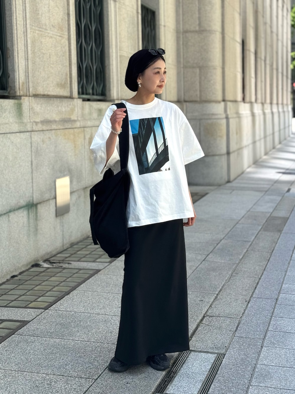 ホワイト系のTシャツ/カットソー、ブラック系のスカート、ブラック系のトートバッグを着用したレディースの春コーディネートの5枚目の写真