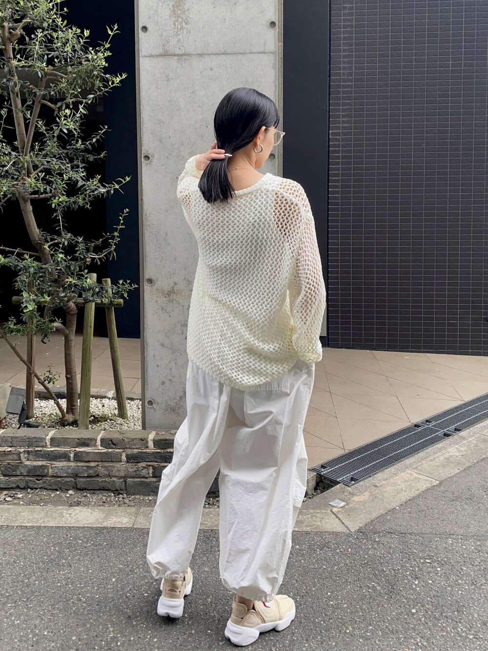 ホワイト系のニット/セーター、ホワイト系のその他パンツ、その他のスニーカーを着用したレディースの夏コーディネートの2枚目の写真