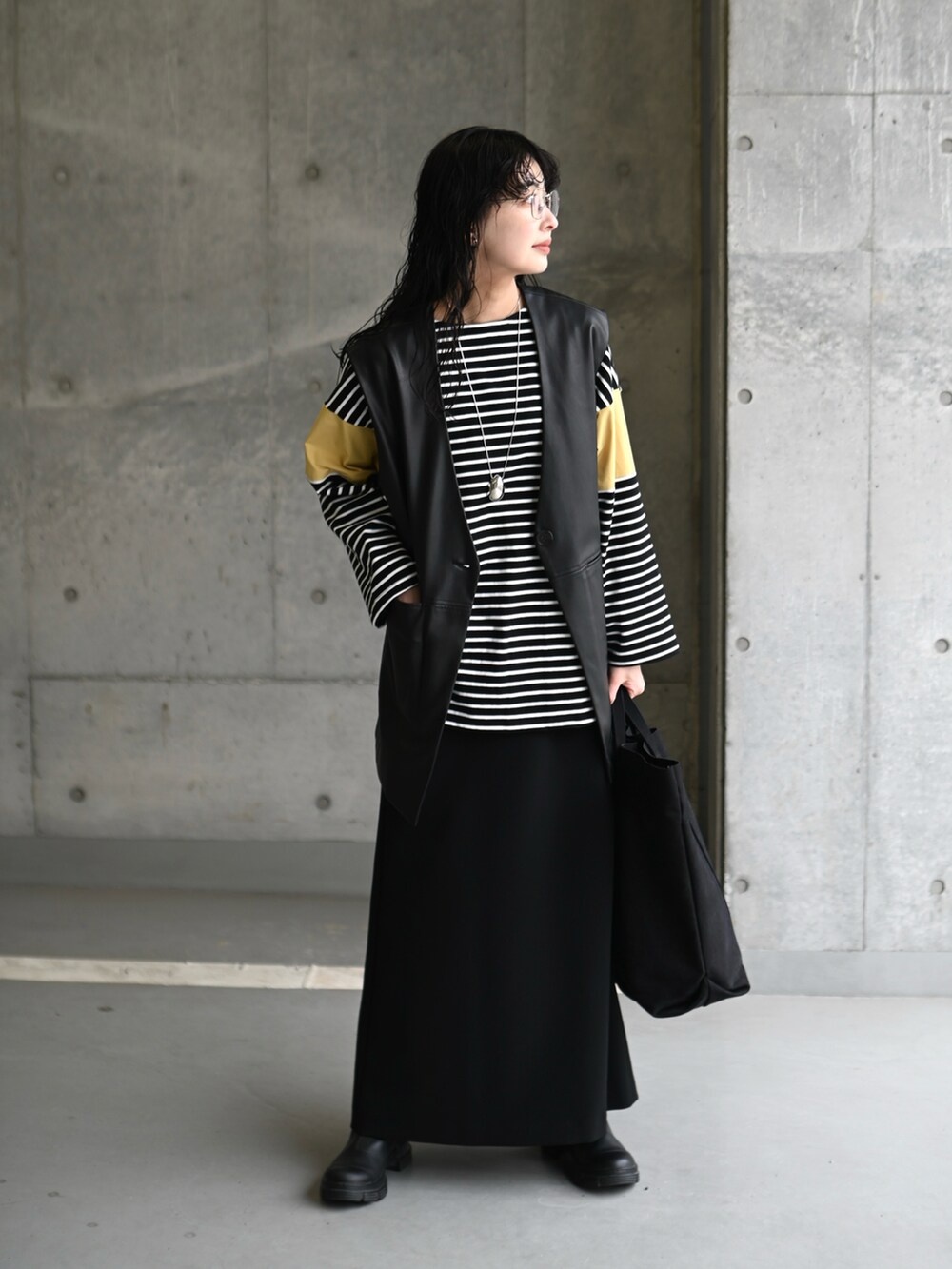 イエロー系のTシャツ/カットソー、ブラック系のスカート、ブラック系のブーツを着用したレディースの春コーディネートの4枚目の写真