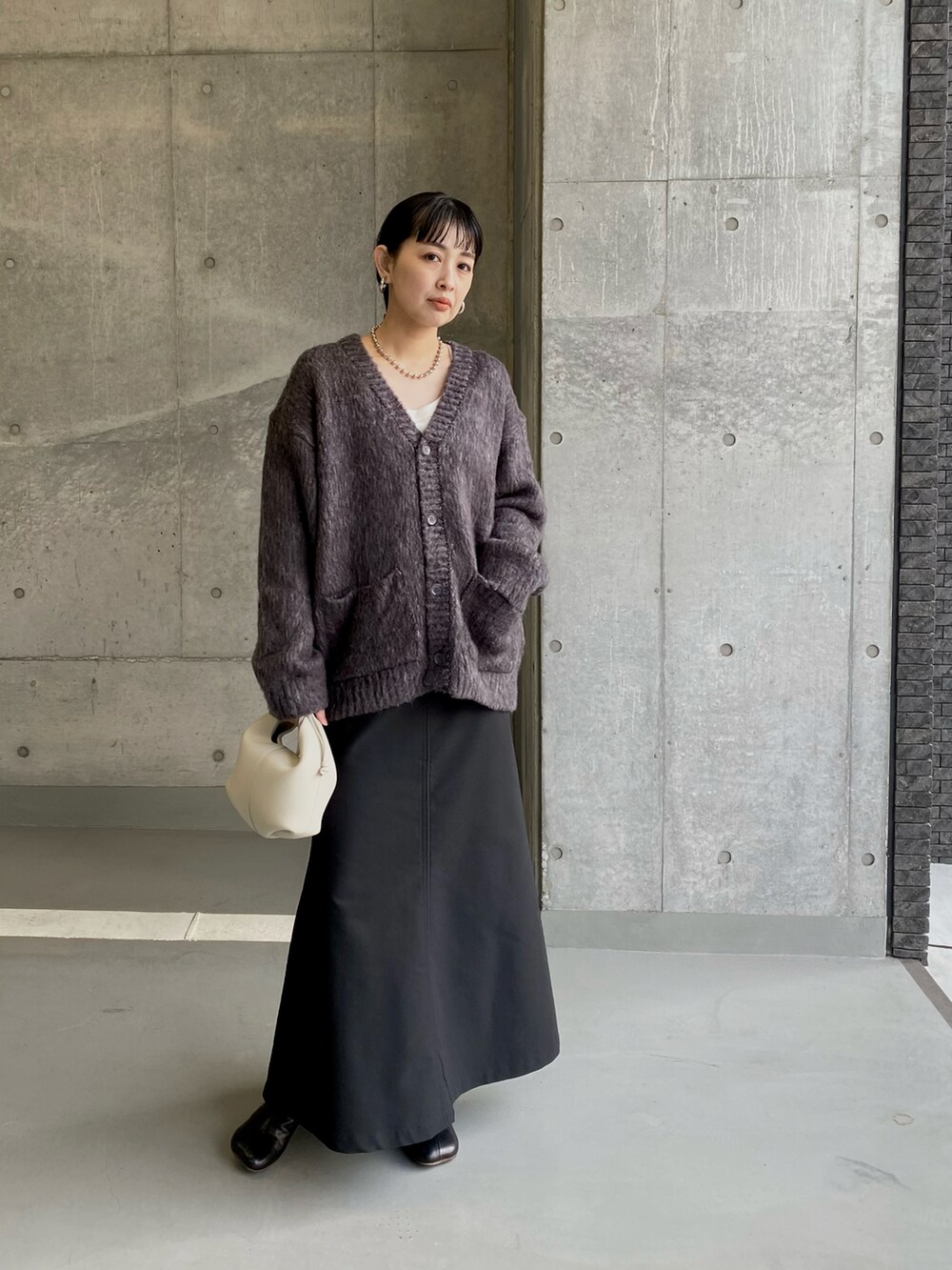 グレー系のカーディガン/ボレロ、ブラック系のスカート、シルバー系のネックレスを着用したレディースの冬コーディネートの3枚目の写真
