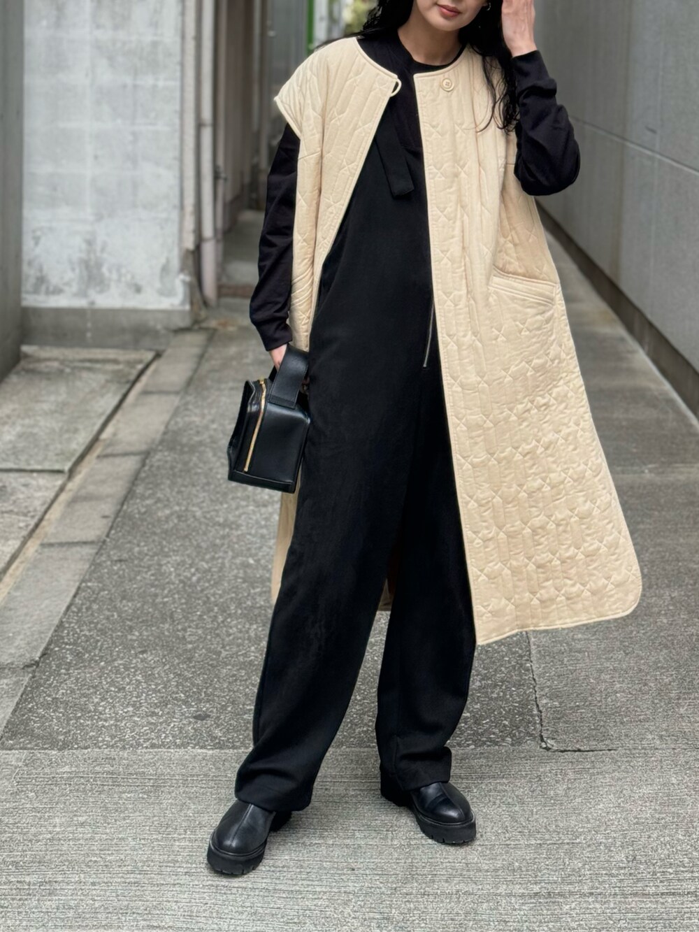 ブラック系のサロペット/オーバーオール、ブラック系のブーツ、ベージュ系のミリタリージャケットを着用したレディースの冬コーディネートの5枚目の写真