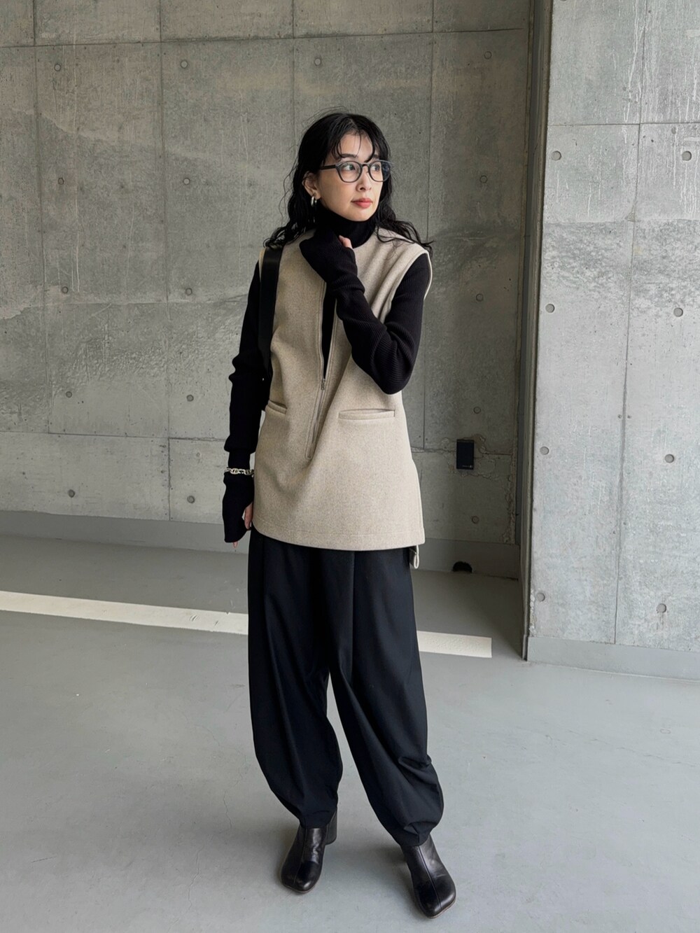 ベージュ系のベスト、ブラック系のスラックス、ブラック系のブーツを着用したレディースの冬コーディネートの5枚目の写真