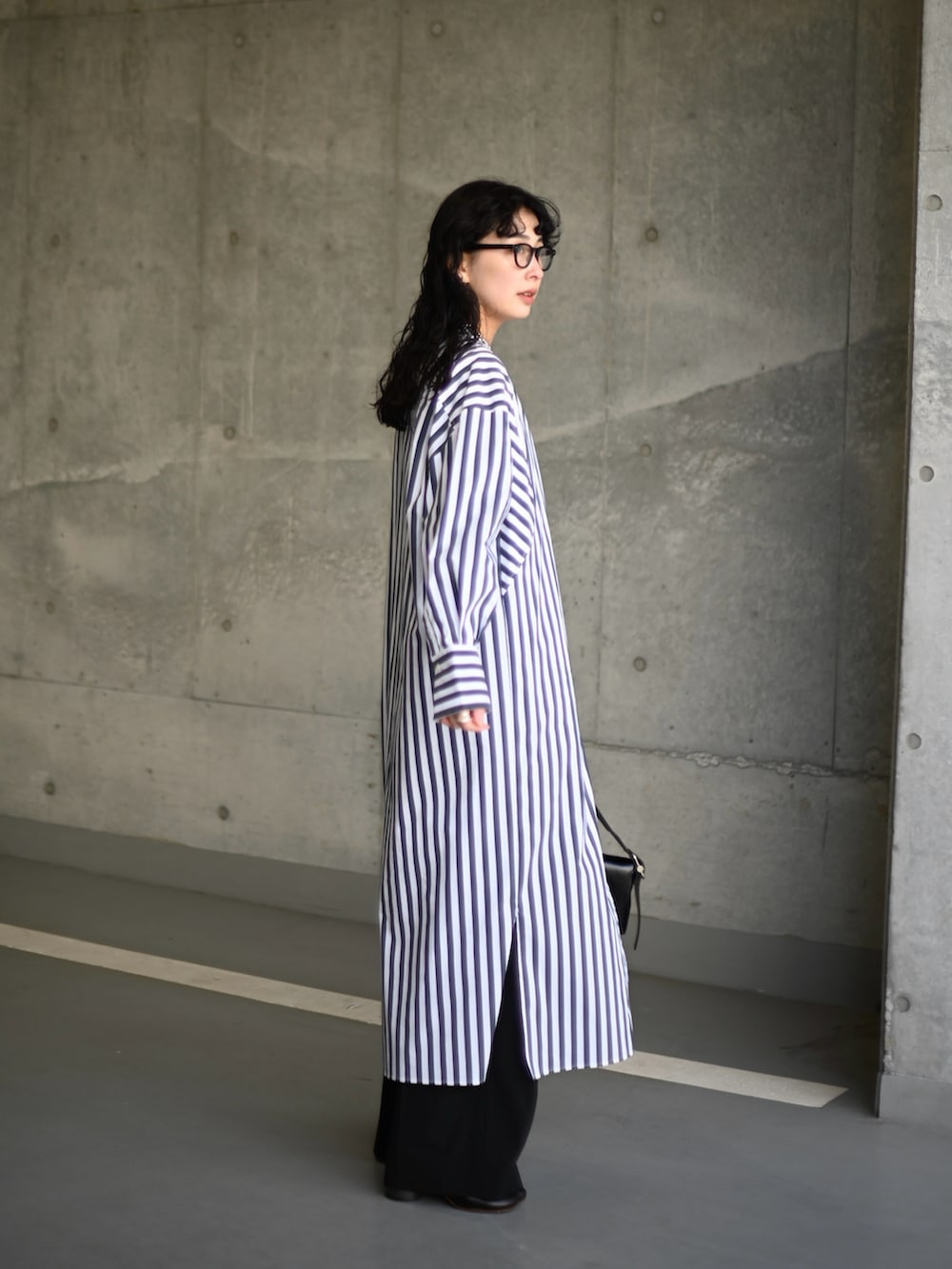 ホワイト系のシャツワンピース、ブラック系のショルダーバッグ、ブラック系のスラックスを着用したレディースの冬コーディネートの3枚目の写真