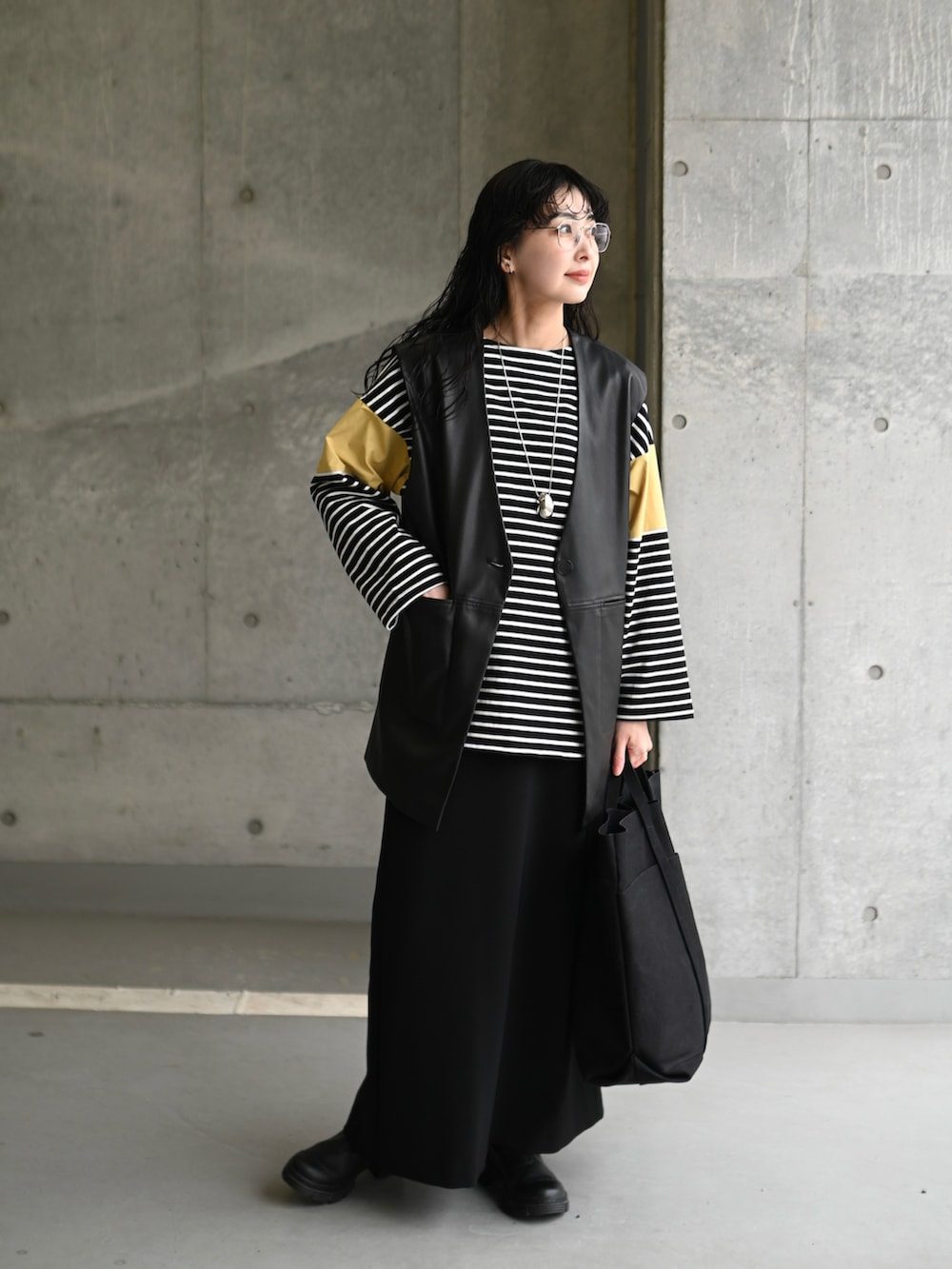 イエロー系のTシャツ/カットソー、ブラック系のスカート、ブラック系のブーツを着用したレディースの春コーディネートの2枚目の写真