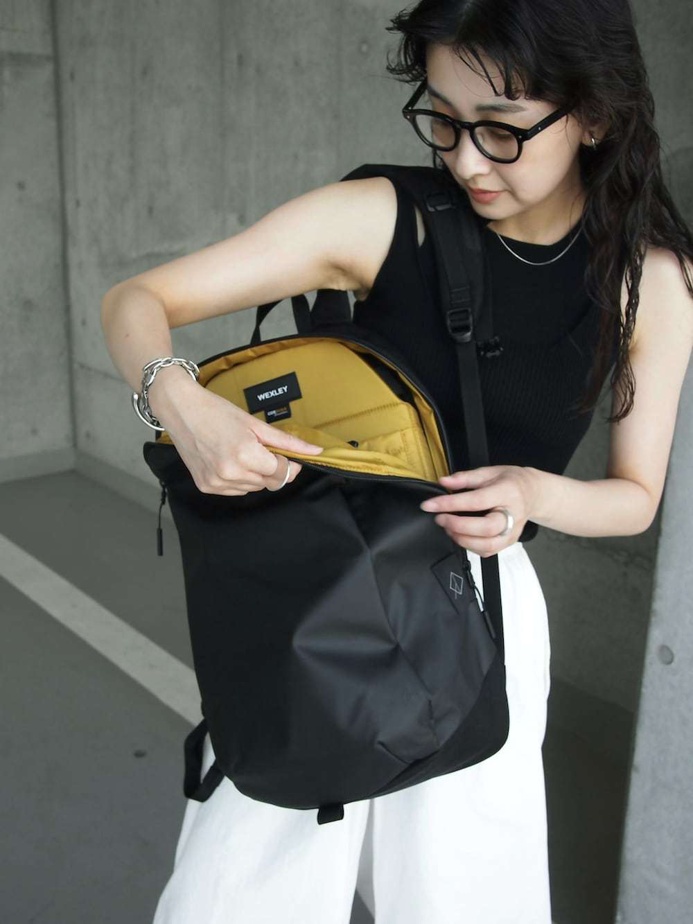 ブラック系のバックパック/リュック、ブラック系のスニーカー、ブラック系のタンクトップを着用したレディースの夏コーディネートの3枚目の写真