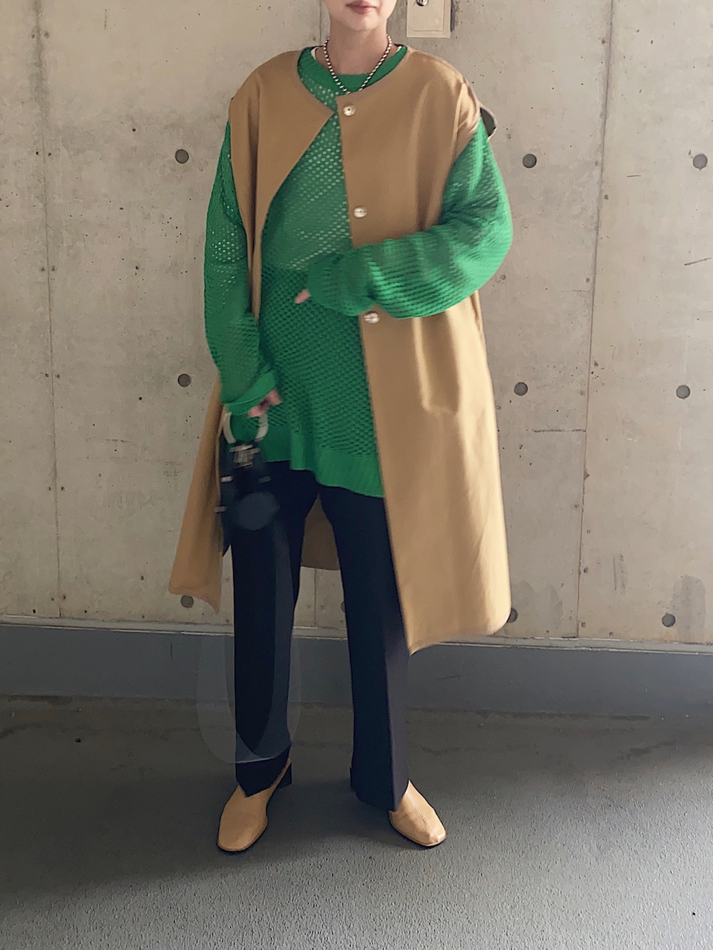 ベージュ系のその他アウター、グリーン系のニット/セーター、ブラック系のその他パンツを着用したレディースの春コーディネートの2枚目の写真