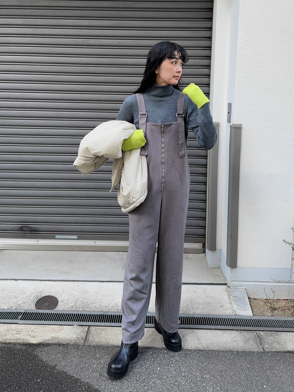 グレー系のサロペット/オーバーオール、グレー系のニット/セーター、ブラック系のブーツを着用したレディースの冬コーディネートの4枚目の写真