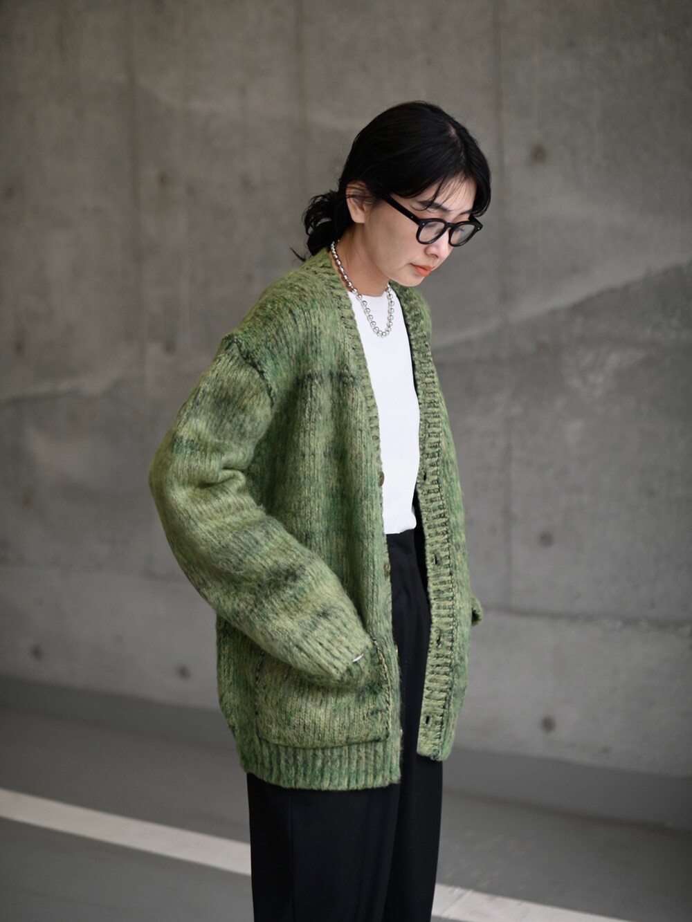 グリーン系のニット/セーター、ブラック系のスラックス、ブラック系のブーツを着用したレディースの冬コーディネートの3枚目の写真